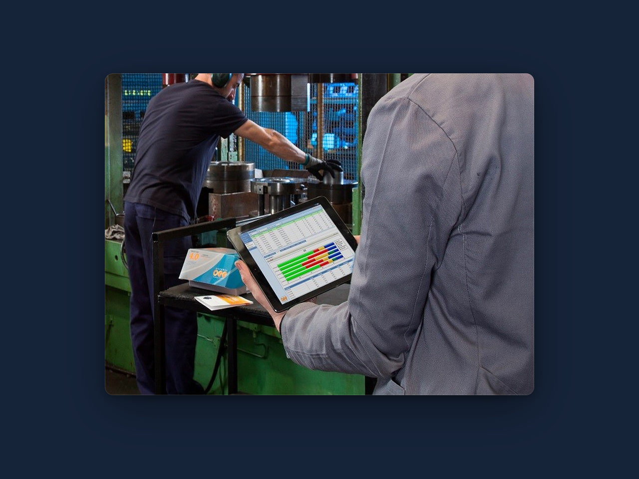 Operario consultando en una tablet los indicadores de producción junto a una máquina inyectora.