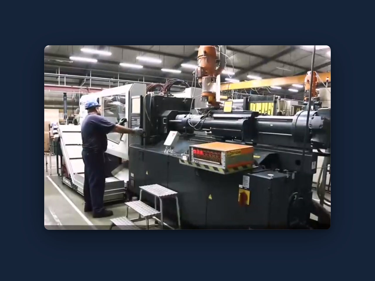 Máquina inyectora de plástico en planta, con un operario durante un cambio de molde.